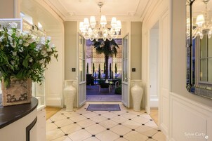 Vestíbulo de hotel con candelabro, una recepción y vistas al área de estar exterior.