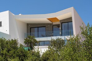 Un edificio moderno con fachada curva, ventanas amplias y un balcón con barandilla de vidrio.