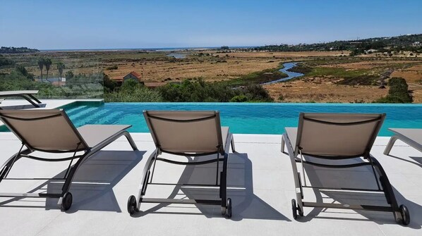 Zona junto a la piscina con sillones de descanso y vista al paisaje.