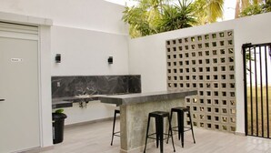 A modern kitchen with a marble countertop, two stools, and a concrete pillar.