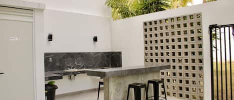 Una cocina moderna con encimera de mármol, dos taburetes y un pilar de hormigón.