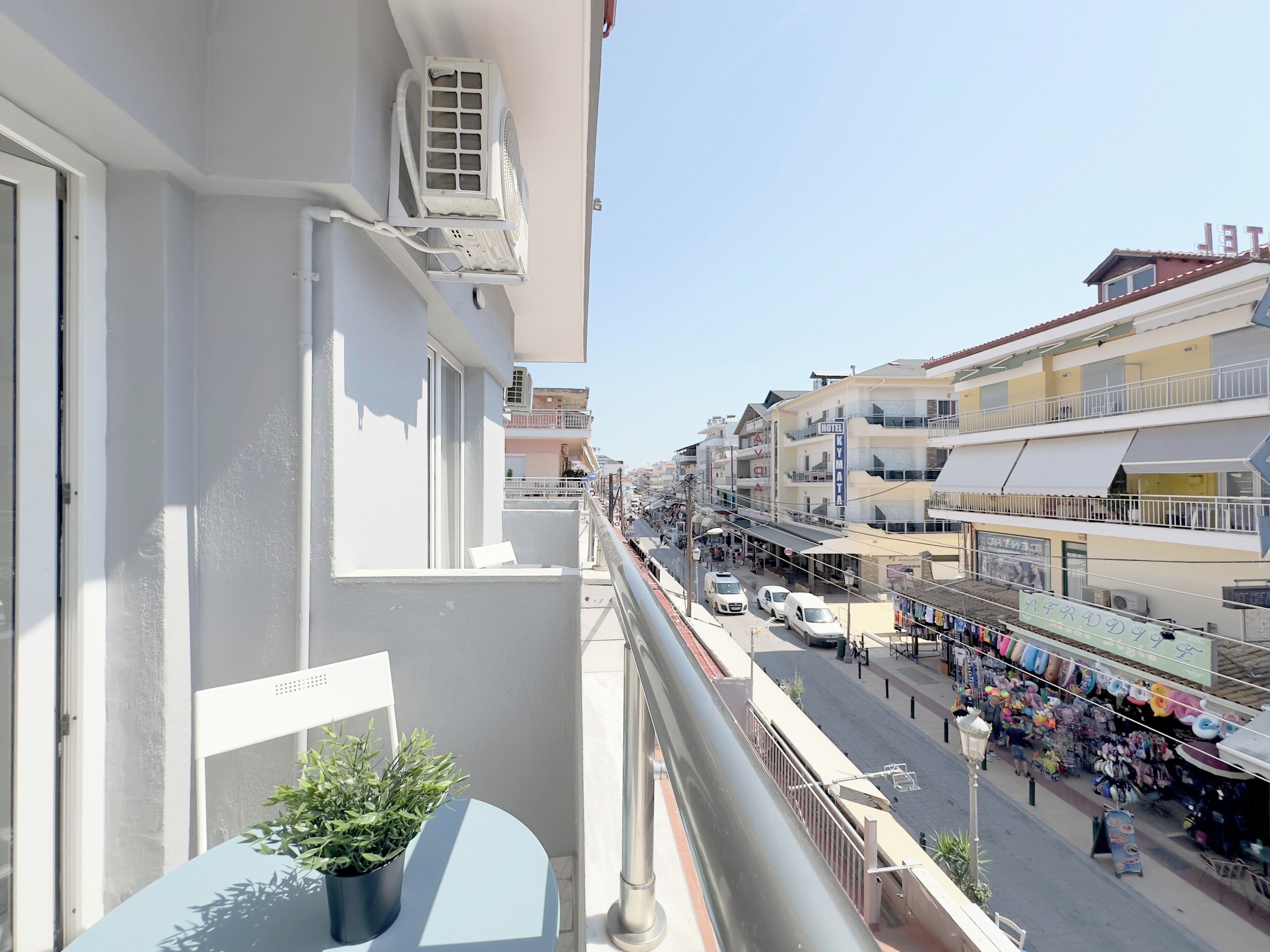 A balcony with a potted plant, a white chair, and a window with an air conditioning unit.