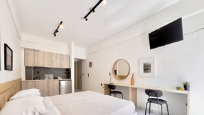 A modern bedroom with a bed, a desk, and a kitchenette. - Seagull by halu! (Katerini)