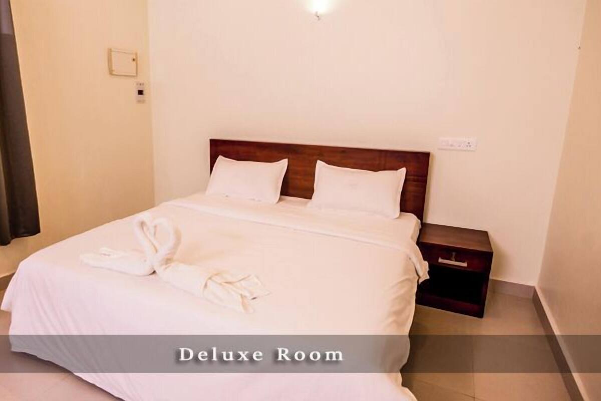 A Deluxe Room with a bed, pillows, a nightstand, and a towel.