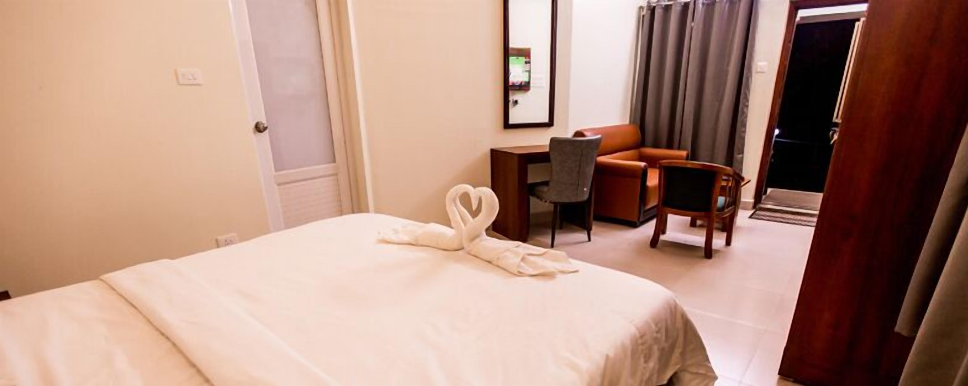 Una habitación de hotel con cama, escritorio, silla y sofá.