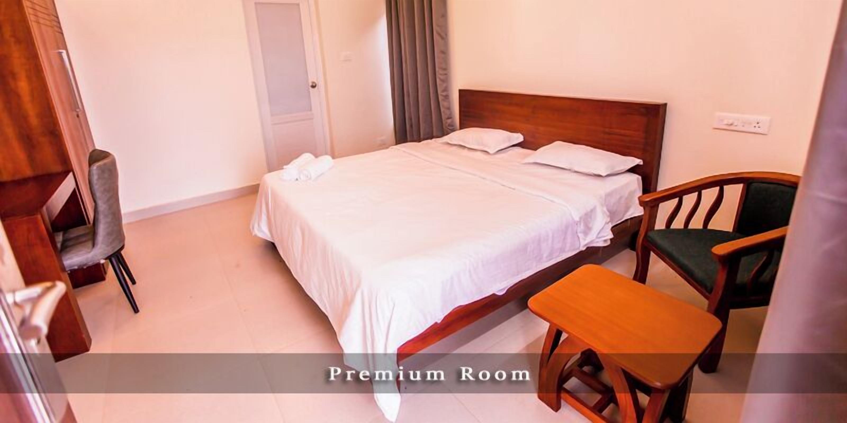 A room with a bed, a chair, a small table, and a door.