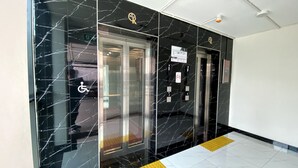 Eine Hotelhalle mit Marmorwänden, zwei Aufzügen und einem Rollstuhlzugang-Schild.
