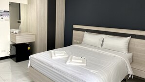 Ein Hotelzimmer mit Bett, Nachttisch, Spiegel und einer kleinen schwarzen Mülltonne.