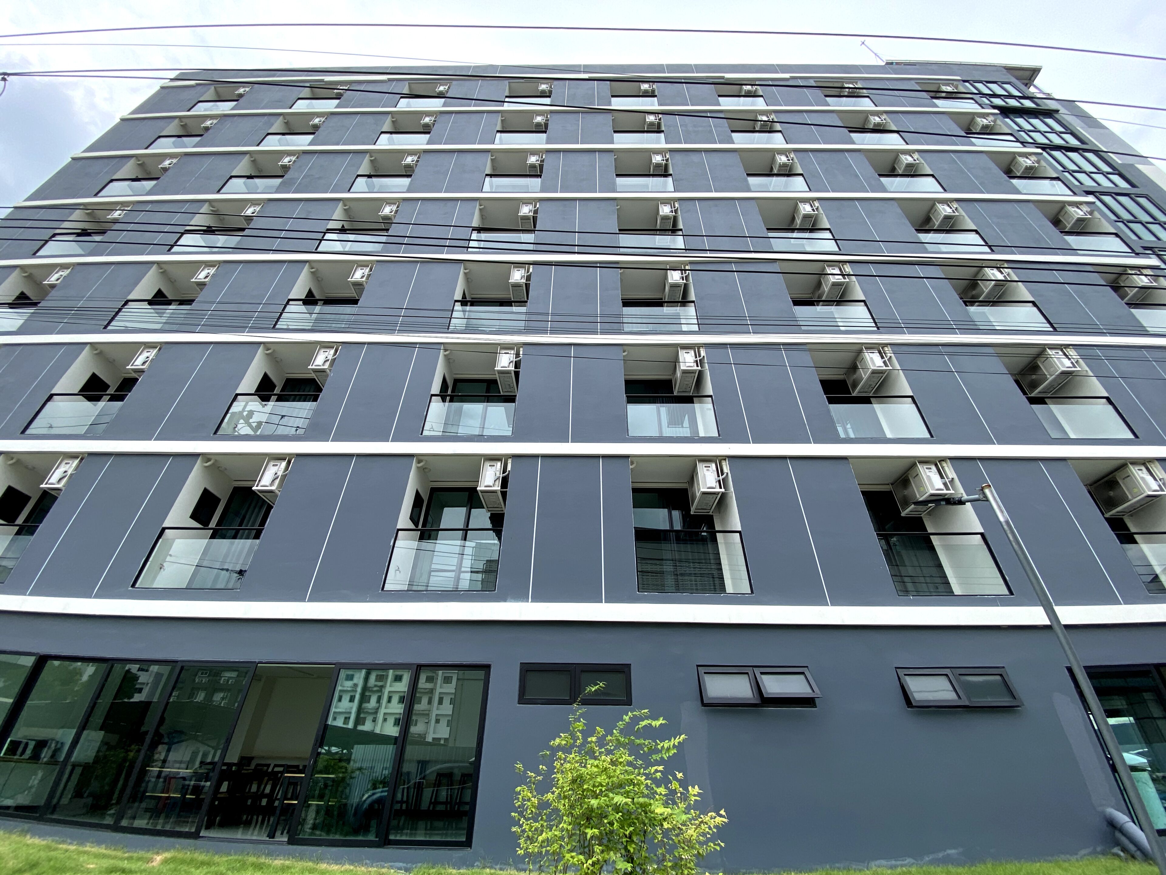 Un edificio moderno de varios pisos con una serie de balcones y unidades de aire acondicionado.