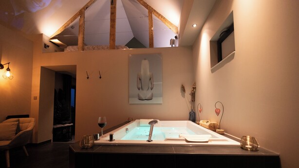 A modern bathroom with a large bathtub, a wooden ceiling, and a framed artwork on the wall. - Chambre d'hôte with private spa, whirlpool bath and infrared sauna (Boëseghem)