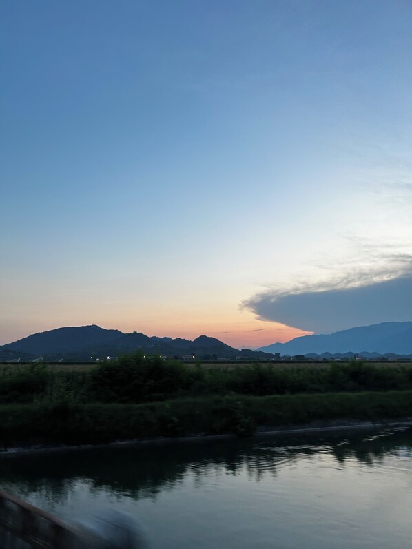 Ein Fluss mit einem Bergpanorama im Hintergrund und einem bewölkten Himmel.