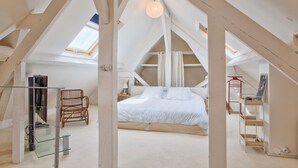 An attic bedroom with a sloped ceiling, a bed, a chair, and a desk with a lamp. - Villa de charme à Benerville - 5 Suites, Garden 1800m² & Beach on foot (Benerville-sur-Mer)