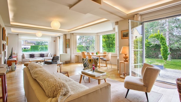 A spacious living room with a sofa, armchair, and dining area. - Villa de charme à Benerville - 5 Suites, Garden 1800m² & Beach on foot (Benerville-sur-Mer)