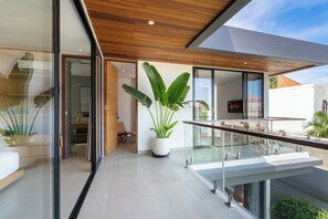 Un interior moderno con balaustrada de vidrio, una planta en maceta y vistas al exterior.