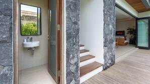A modern interior with a stone accent wall, a wooden staircase, and a minimalist bathroom. - Yoki Villa by Betterplace (Canggu)