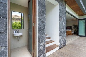 A modern interior with a stone accent wall, a wooden staircase, and a minimalist bathroom. - Yoki Villa by Betterplace (Canggu)