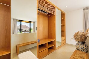 Una habitación moderna con un armario de madera, un banco y un espejo grande.