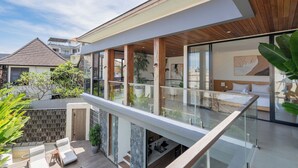 A modern hotel with a spacious balcony, a kitchen area, and a bedroom with a large window. - Yoki Villa by Betterplace (Canggu)