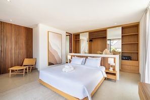 Un dormitorio moderno con una cama grande, cabecera de madera, mesita de noche con lámpara, una silla y un espejo amplio.