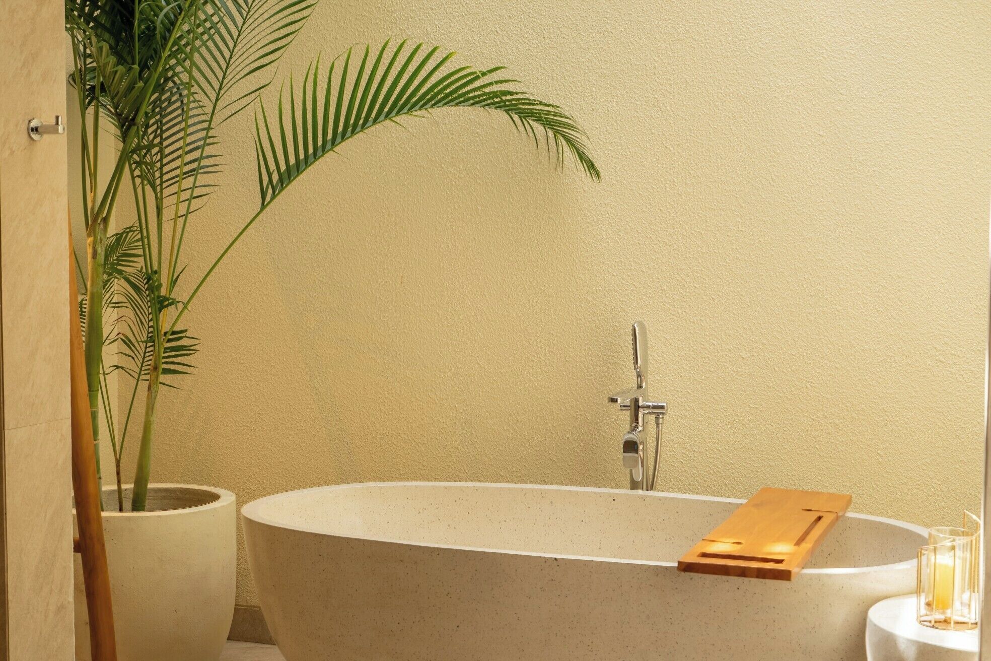 A bathroom with a freestanding bathtub, a potted plant, and a glass candle holder.