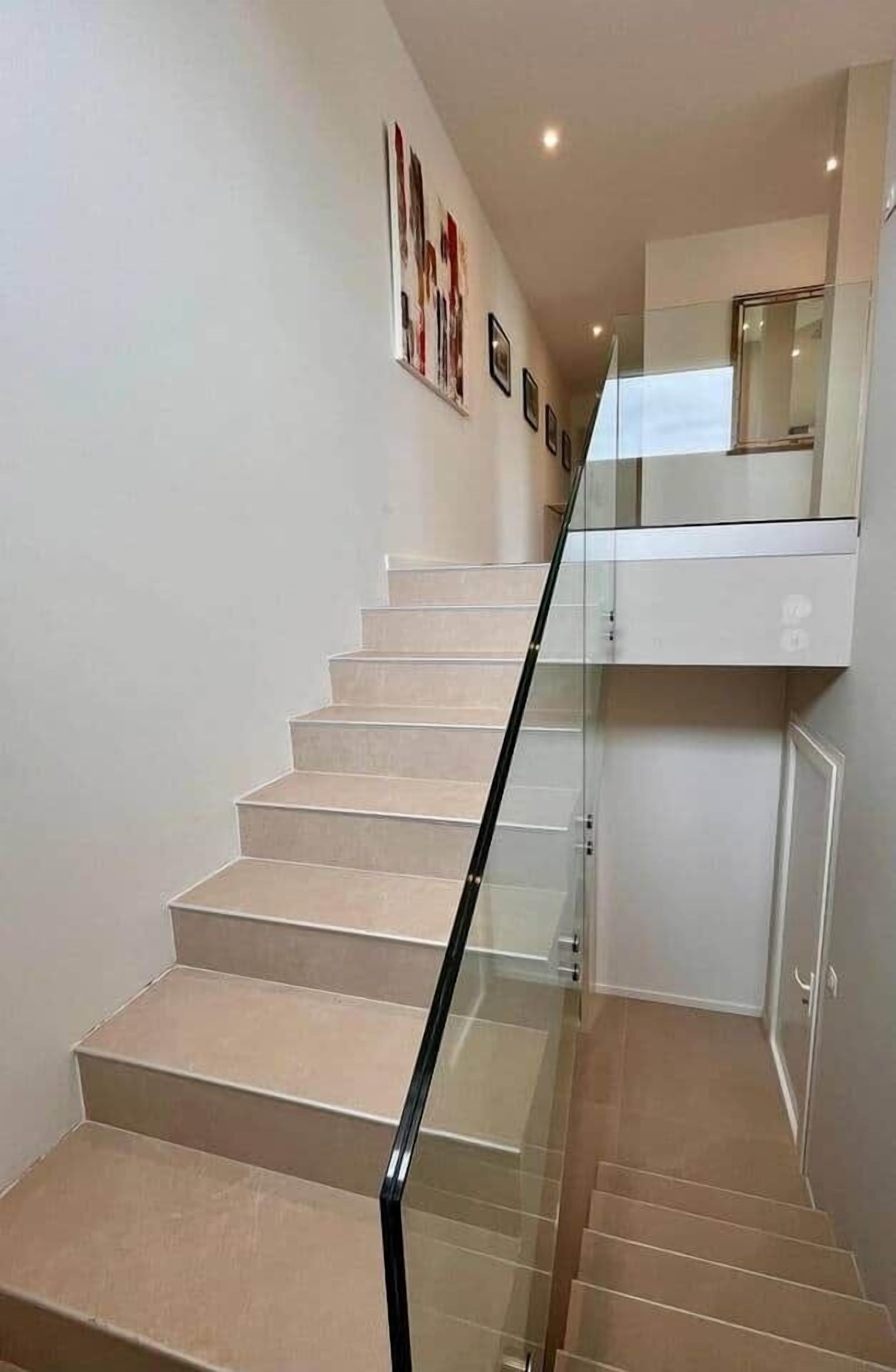 A modern staircase with glass railings and beige steps.