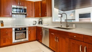 A modern kitchen with wooden cabinets, stainless steel appliances, and a large window. - Snowcreek Townhome with Back Deck, Foosball Table, and Mountain Views! (Mammoth Lakes)