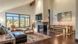 A spacious living room with a fireplace, large windows, and a dining area. - Snowcreek Townhome with Back Deck, Foosball Table, and Mountain Views! (Mammoth Lakes)