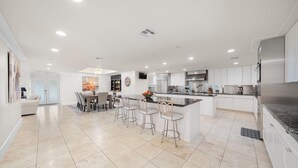 A modern kitchen with a central island, bar stools, and a dining area with a chandelier.