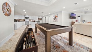 A modern living area with a pool table, a billiards rack, and a sofa.