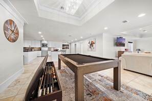 A modern living area with a pool table, a billiards rack, and a sofa.