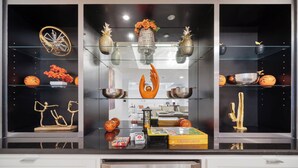 A kitchen with glass-fronted shelves displaying decorative items, a central vase, and a variety of kitchenware.