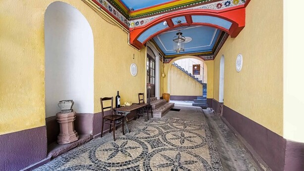 Un pasillo con piso estampado, una escalera y una mesa con sillas.