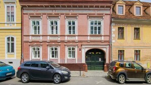Un edificio con fachada rosa, múltiples ventanas y una puerta doble verde.