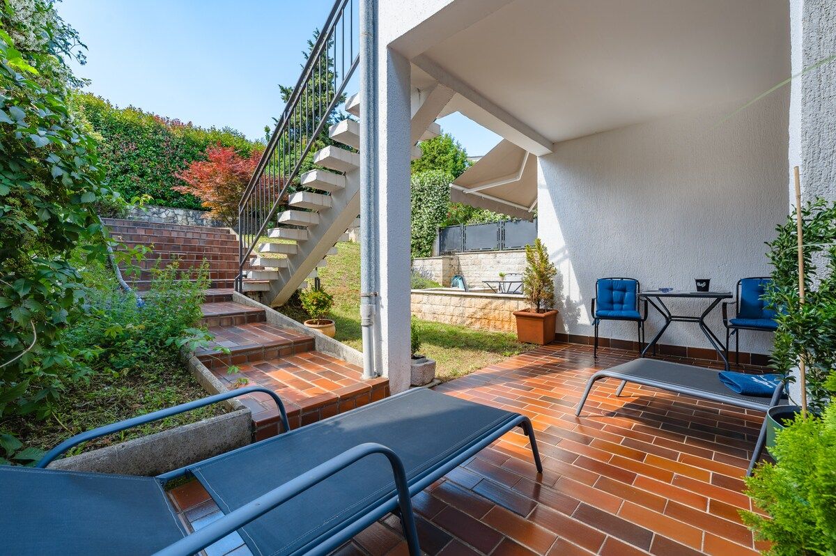 A patio area with a brick floor, outdoor seating, and a staircase leading to a higher level.