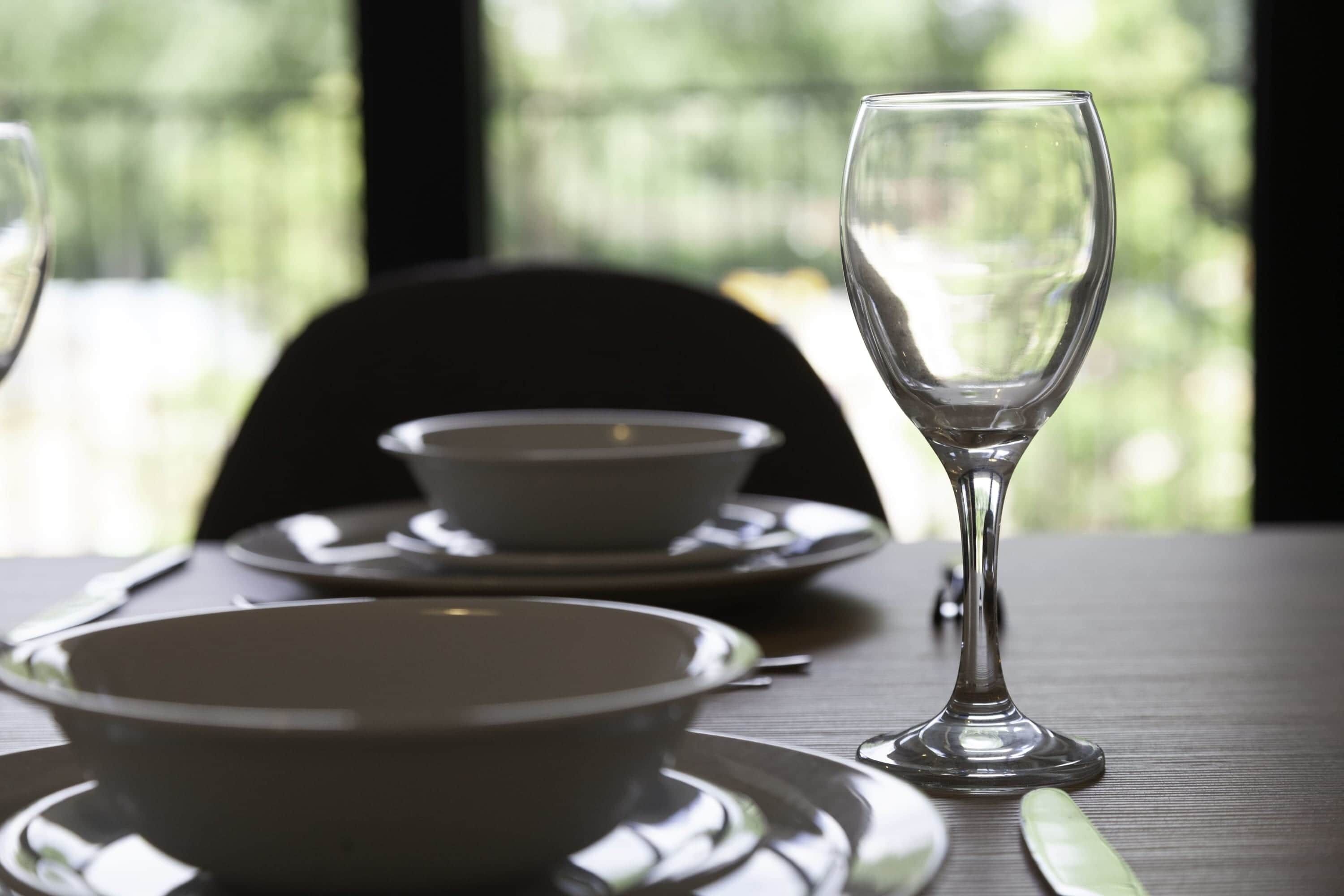 A dining table with a glass, a bowl, and a plate.