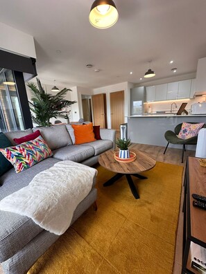 A modern living room with a grey sofa, a round wooden coffee table, and a yellow rug. - Stylish 1 Bedroom Apartment in Central Ashford (Ashford)