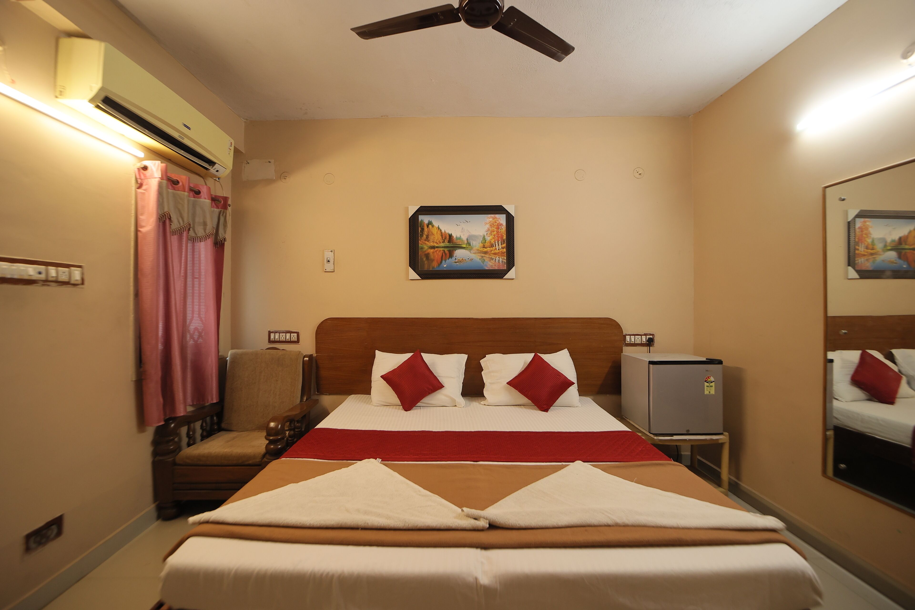 A hotel room with a bed, a chair, a heater, and a ceiling fan.