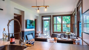 Una cocina moderna con una isla grande, una zona de comedor con sofá y un televisor montado en la pared.