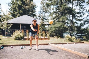 A person playing croquet in an outdoor setting with a house in the background.