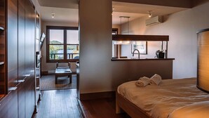 Quarto de hotel moderno com uma cama grande, um espaço de estar pequeno e vista para o exterior.