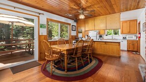 A wooden interior with a dining table, chairs, and a kitchen area. - Rustic retreat in a convenient location! (Shaver Lake)