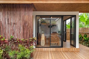 A modern interior with a glass door leading to a dining area, wooden flooring, and a bamboo wall. - Cove Dmali (Ungasan)