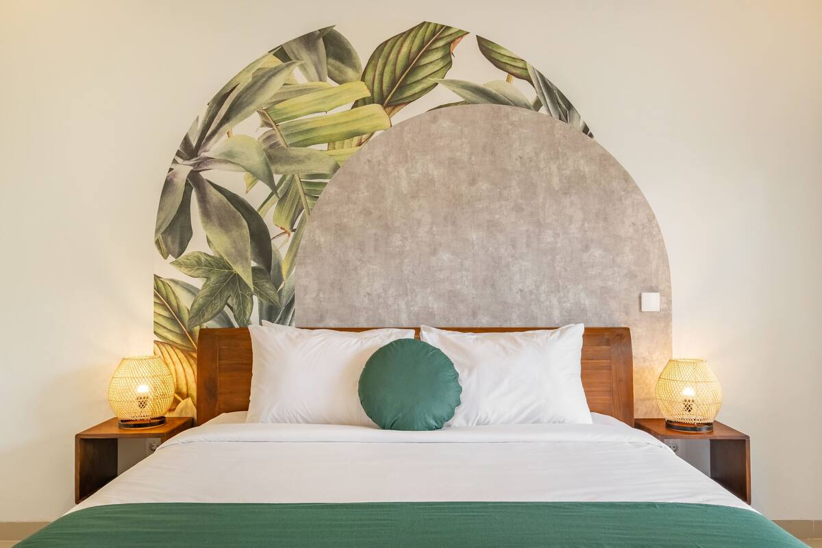 A bed with white bedding, a green pillow, and a large circular wall decoration.