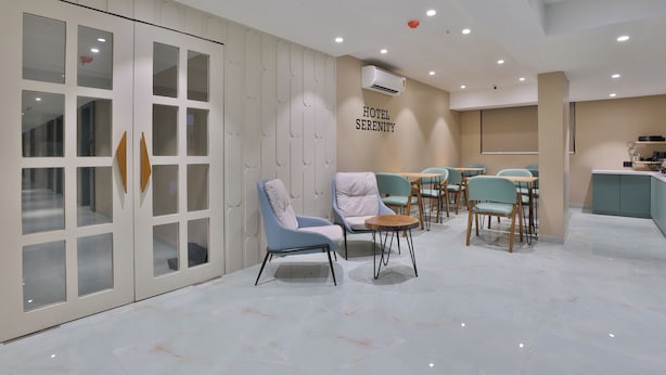 Eine moderne Hotellobby mit einer Rezeption, einer Sitzecke und einer Wand mit dem Hotelnamen.