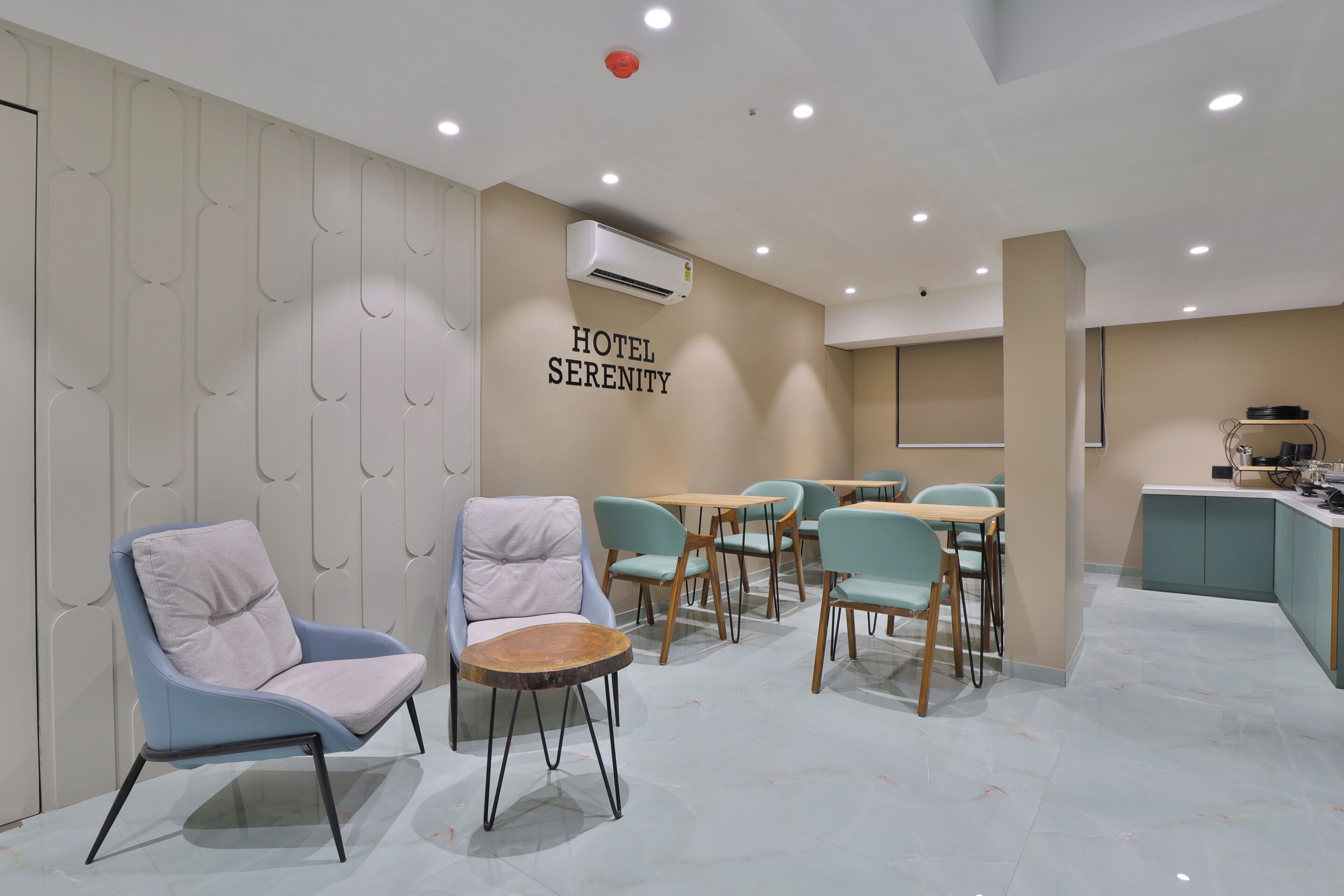 A hotel lobby with seating areas, a reception desk, and an air conditioning unit on the wall.