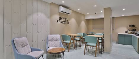 A hotel lobby with seating areas, a reception desk, and an air conditioning unit on the wall.
