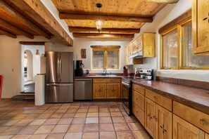 Una cocina con armarios de madera, un refrigerador de acero inoxidable, un lavavajillas y piso de baldosas.