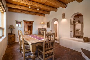 Un comedor rústico con una mesa de madera, sillas y un corredor con estampado.