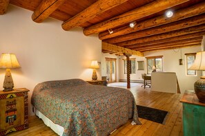 Un dormitorio con una cama grande, vigas de madera en el techo y dos lámparas de noche.