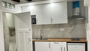 Una cocina moderna con armarios blancos, encimera de madera y lavavajillas integrado.